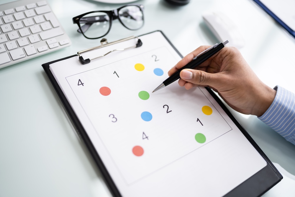 Hand completing cognitive assessment test on clipboard with numbered colored dots and checkmark, representing neuropsychological screening process