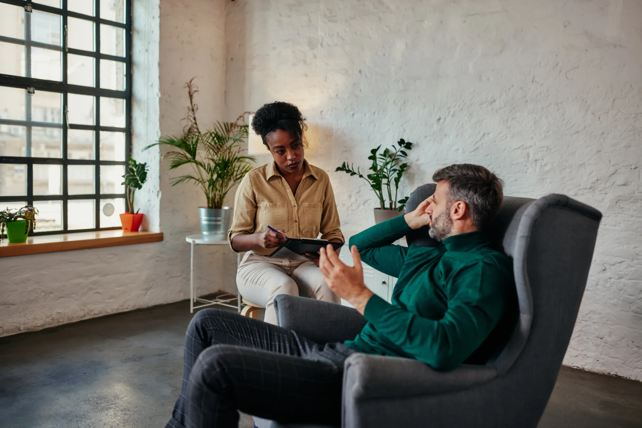 Therapist conducting a psychotherapy session with adult client in a comfortable, private office setting