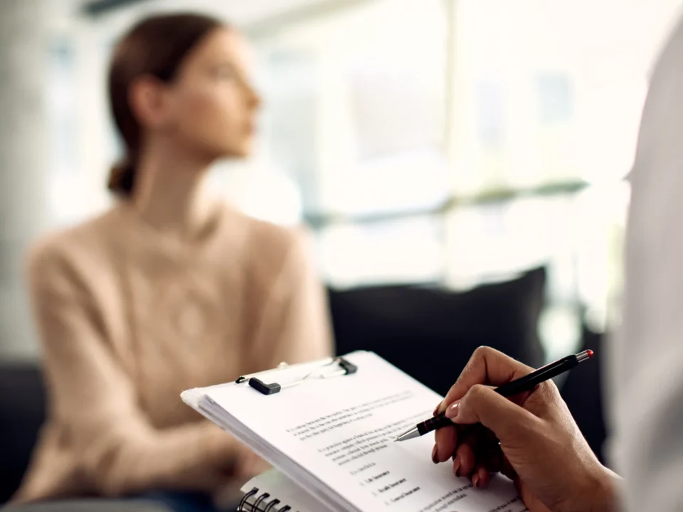 A psychologist takes notes on a clipboard during a patient consultation, representing the collaborative nature of psychotherapy for mental health support.