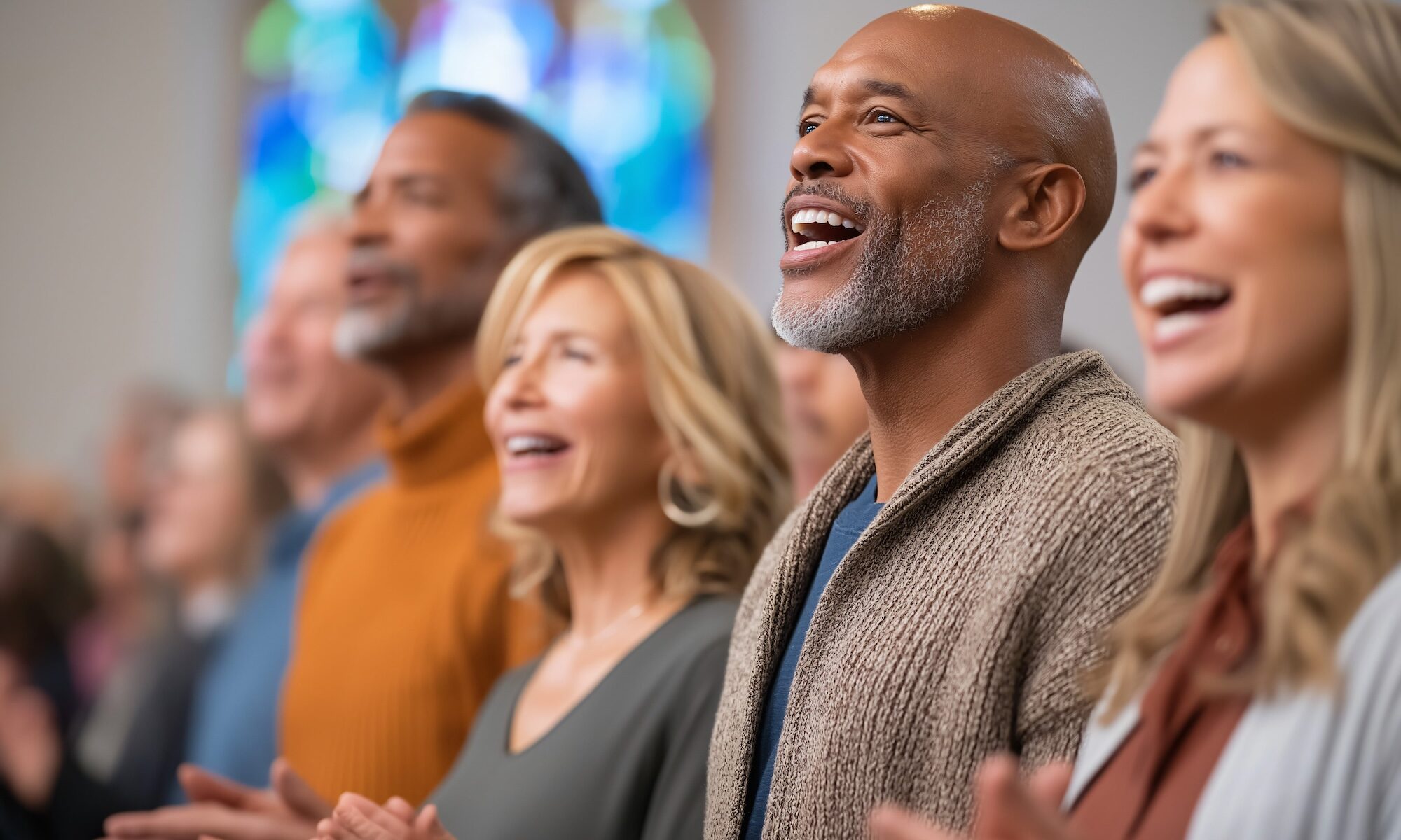 Diverse group of adults smiling and clapping together during a worship service, illustrating the cognitive and mental health benefits of faith community involvement