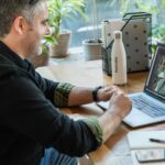 Adult male at a home desk on a video call with a therapist, illustrating what virtual cognitive rehabilitation therapy looks like