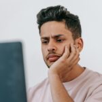 A man with a concerned expression looking at his laptop, reflecting the growing trend of people turning to AI tools like ChatGPT to research cognitive health symptoms.