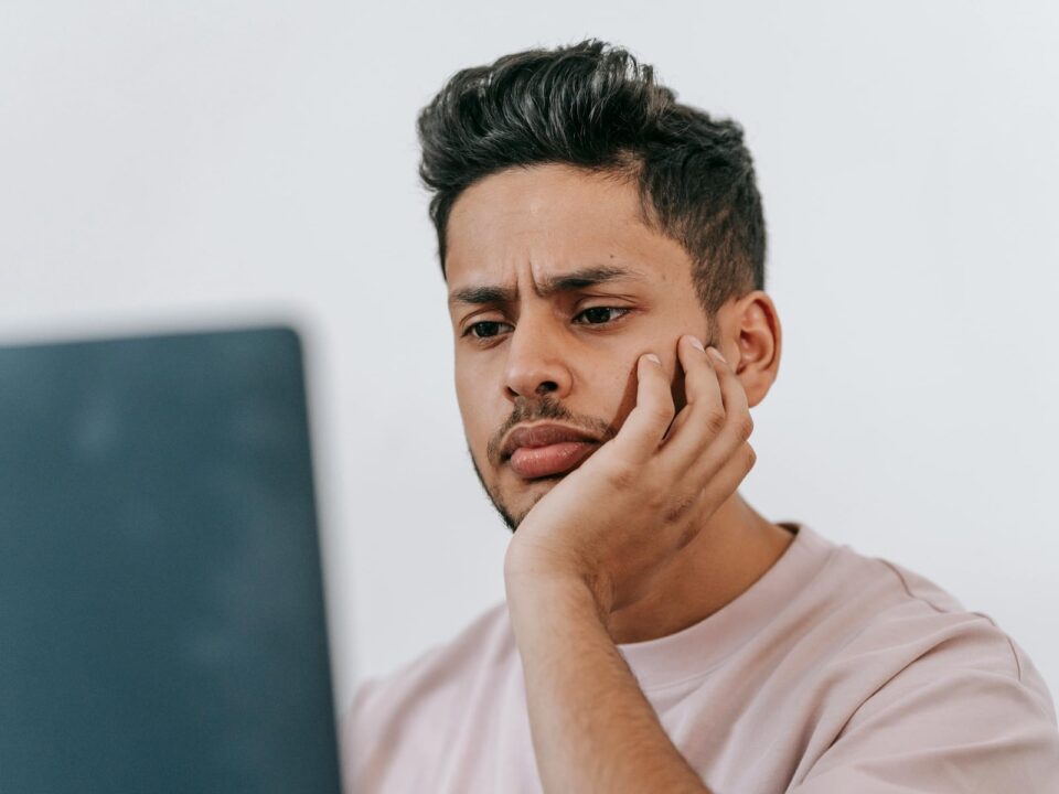 A man with a concerned expression looking at his laptop, reflecting the growing trend of people turning to AI tools like ChatGPT to research cognitive health symptoms.