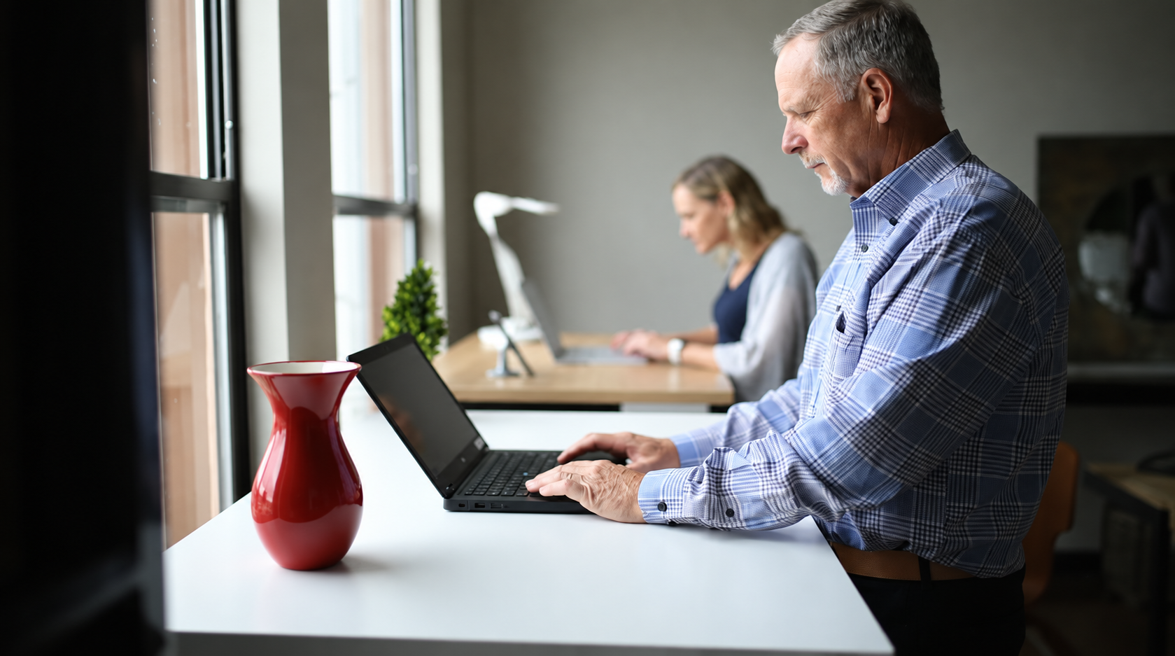 Older man working on a laptop in a bright office